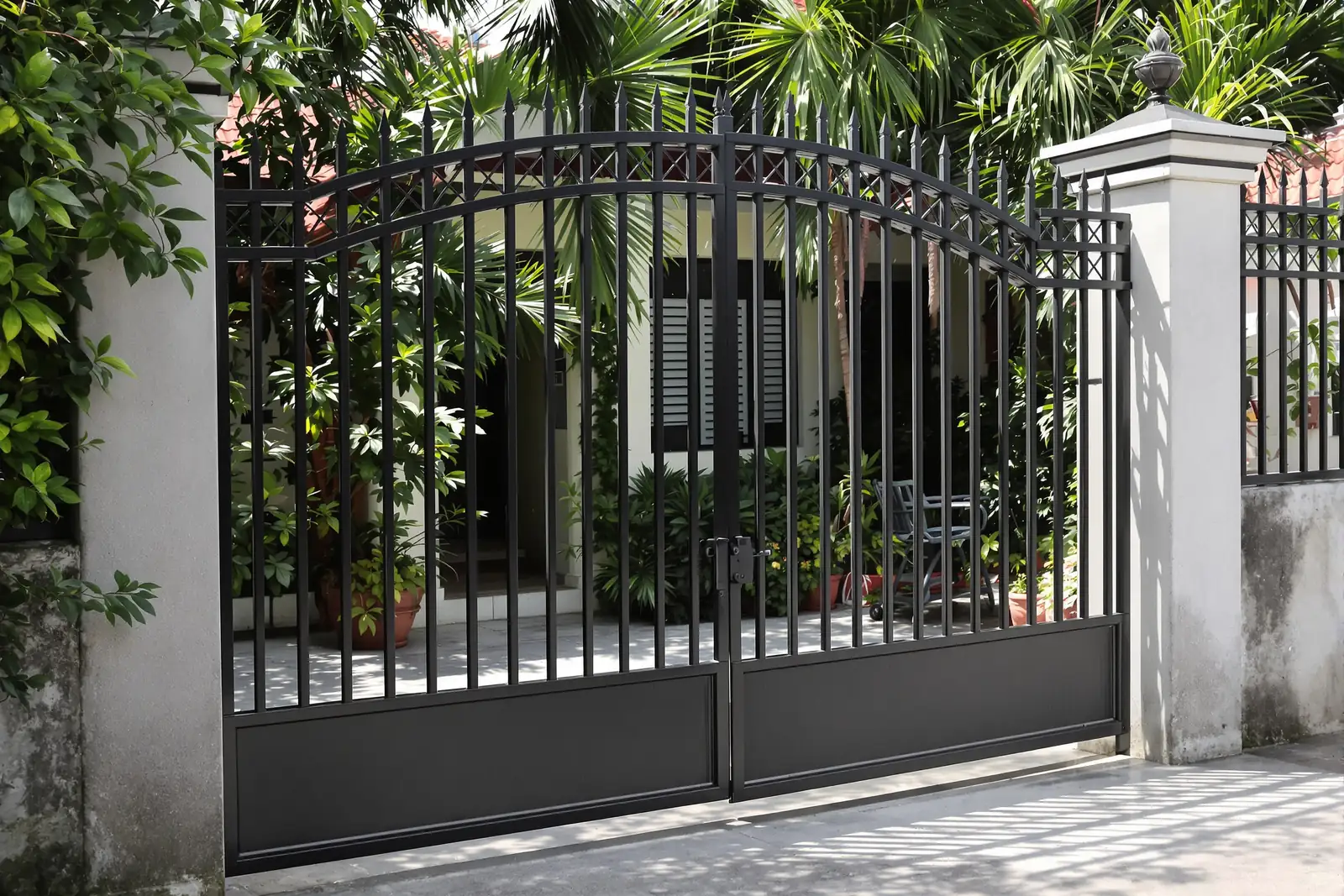 Black double swing gate of vertical bars with a solid lower panel