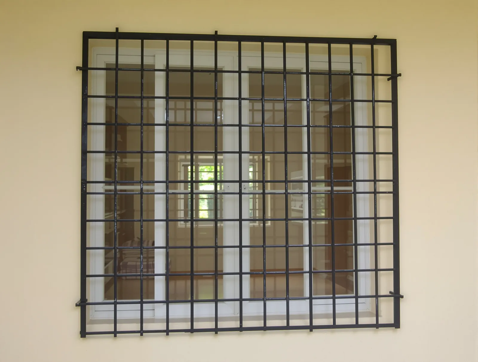 Black steel window grill with a square grid pattern