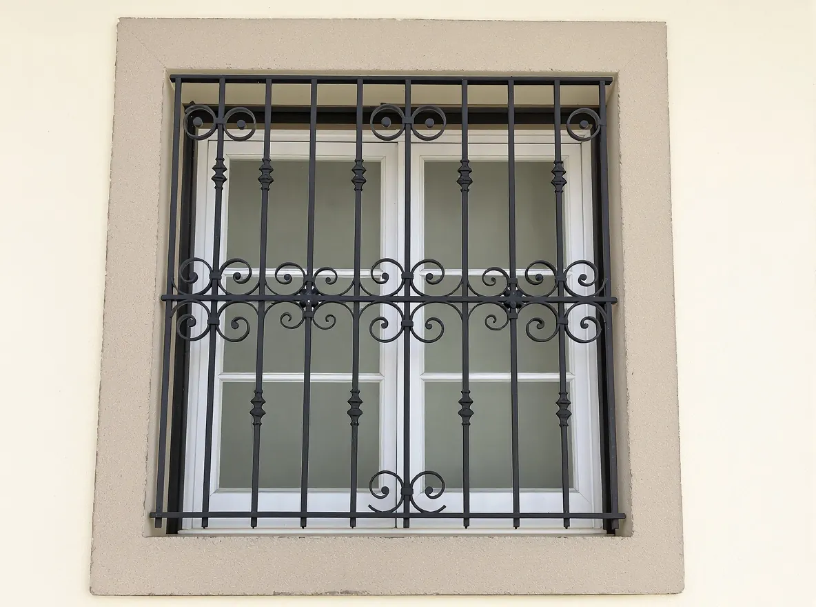 Classic black window grill with scrolls on a cream wall